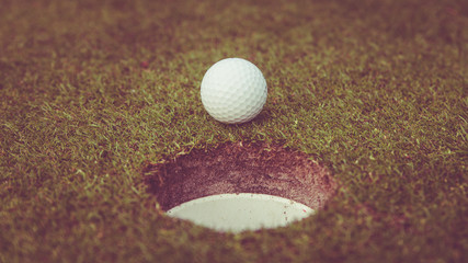 golf ball on lip of cup. Golf ball on green grass in golf course