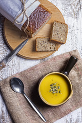 Pumpkin soup in a brown, ceramic bowl on a wooden table view fro