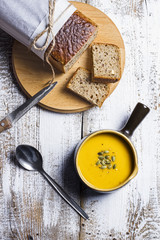 Pumpkin soup with bread on a white rustic table