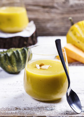 pumpkin soup in a glass on a wooden rustic table