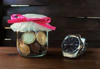 coins faling from glass bottle on the wood table © maria