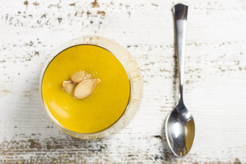 pumpkin soup in a glass on a wooden rustic table, view from top