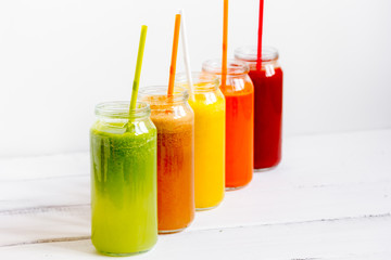 Fresh detox juices glass in row bottles on white background
