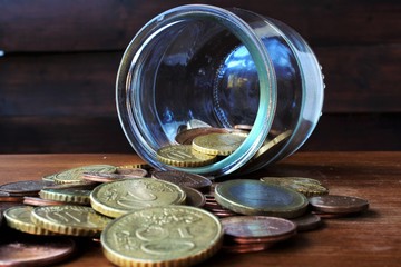 coins faling from glass bottle on the wood table © maria