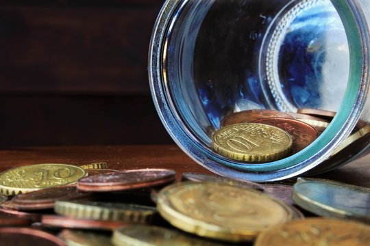 coins faling from glass bottle on the wood table