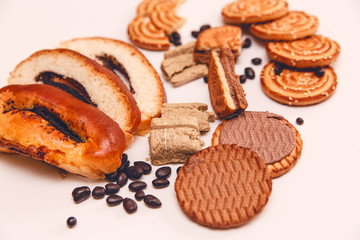 There are Pieces of  Roll with poppy seed,Cookies,Halavah,Chocolate Peas,Tasty Sweet Food on the White Background.Toned pink