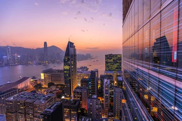 Foto op Plexiglas Hong-Kong Spectaculaire luchtfoto van Victoria Harbour, wolkenkrabbers en de skyline van Hong Kong & 39 s nachts. Skyline weerspiegeld in glazen gevel van een modern gebouw.