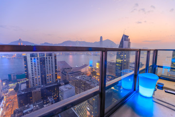 Obraz premium Hong Kong, China - January 1, 2016: spectacular aerial view of Victoria Harbor skyline at sunset from the rooftop of Eye Bar, a modern skybar inside iSquare shopping center in Kowloon, Hong Kong city.