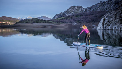 Una mujer practica paddle surf en un lago de montaña