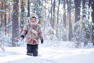 Fototapeta na wymiar Portrait of little boy playing outdoors in winter forest