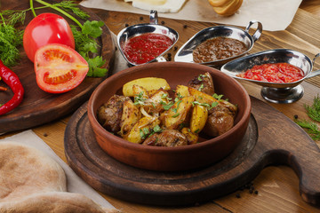 Fried potatoes with meat in brown bowl on a table