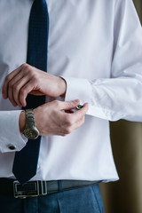 man in a tux fixing his cufflink