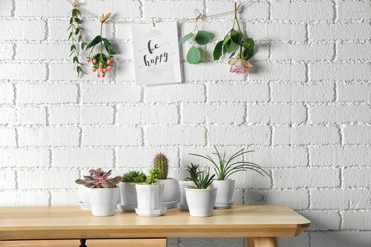 Floral composition of succulents and cactus with greeting card on white brick wall background