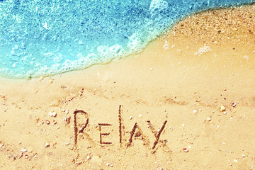 Word RELAX on beach sand
