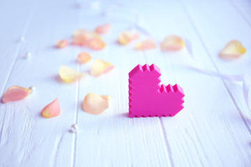 Pink heart with flower petals on table
