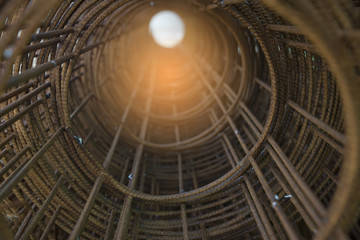 Rolls of wire mesh steel for construction put a pile on the ground, against construction site background.