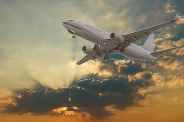 Commercial airplane flying with clouds and sun rays background