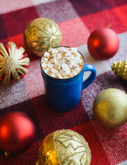 view from above cup of cocoa with marshmallows on red checkered background