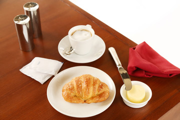 Croissant, butter and cup of coffee on the table