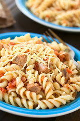 Rotini pasta with tuna and tomato sauce and grated cheese on top, photographed with natural light (Selective Focus, Focus in the middle of the first dish)