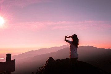 The silhouette of a woman in a yoga pose on the mountain at the Sunset.