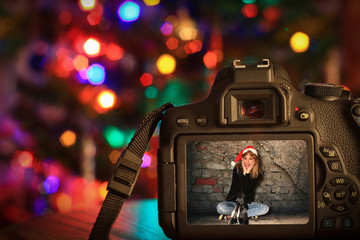 Christmas scene of a digital camera in front of a Christmas tree.