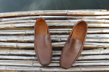 Brown shoe on bamboo wood over pond