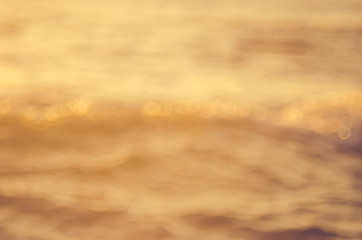 Blur tropical sunset beach with bokeh sun light wave abstract background.