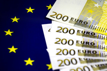 Two hundred euro bills lying in a row on european community flag.  Close up image. Selective focus.
