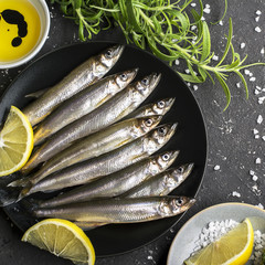 Fresh sea fish smelt or sardines ready for cooking with lomtikmi lemon, thyme, rosemary and coarse  salt. The concept of , healthy seafood. Top view