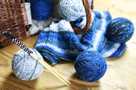 balls of wool and knitting needles on background