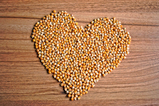 Popcorn kernels in a heart shape on a wooden table