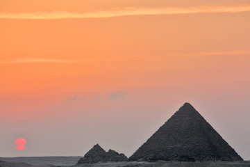 Fototapeta na wymiar Dramatic sunset behind distant Egyptian pyramids in Giza, Cairo, Egypt 