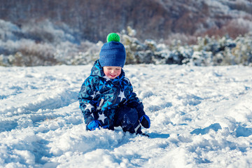 Fototapeta na wymiar Cheeked happy toddler child touches the snow