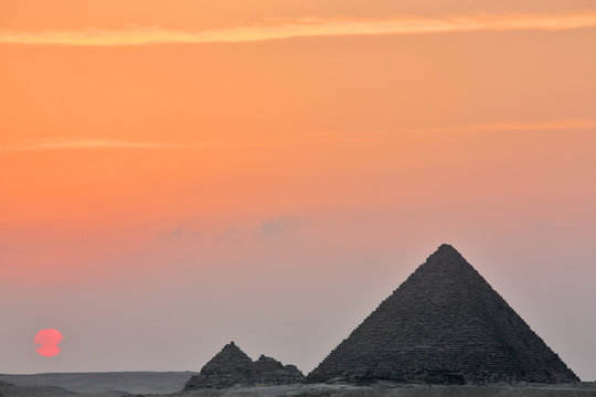 Dramatic sunset behind distant Egyptian pyramids in Giza, Cairo, Egypt
