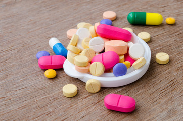 Close up colorful medicine capsule pill on wood background.