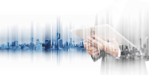 Businessman working on digital tablet with double exposure city, concepts of technology business development