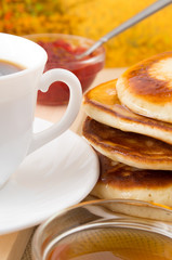 Hot pancake topped with honey and white cup of tea