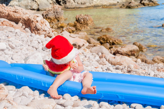 Child in Santa hat on the beach