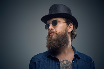 Tattooed bearded male in sunglasses and top hat.