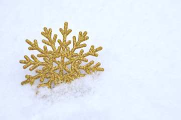 Golden glitter snowflake in snow. Christmas concept
