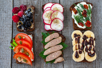 Top view of open sandwiches. Bread with nuts, bananas, berries, sausage, cheese, vegetables. Perfect for the detox diet or just a healthy meal.  Love for a healthy raw food concept.