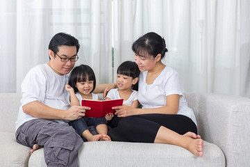 Happy Asian Chinese family reading book on the couch