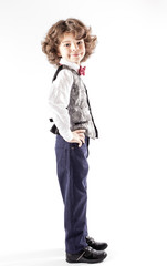 Cute curly boy stands sideways to the camera and looking into the camera. Full length. White background.