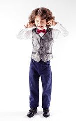 Curly boy is crying and closing her eyes and ears. Gray background.