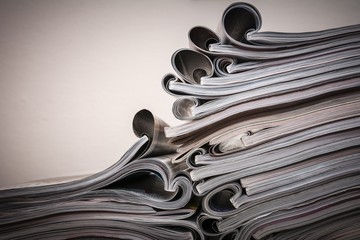 Several magazines opened and then stacked forming a pile with curls of paper