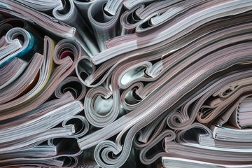 Several magazines opened and then stacked forming a pile with curls of paper