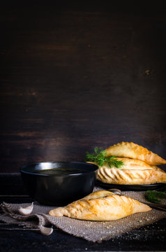 Kibinai, kybyn, kybynar, cheburekki - traditional pastries filled with mutton on dark wooden background. Lithuania. Free space for your text