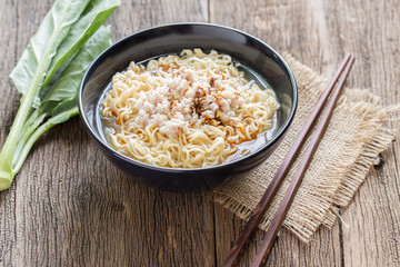 Instant noodles in a cup on a wooden table.Garnish with minced p