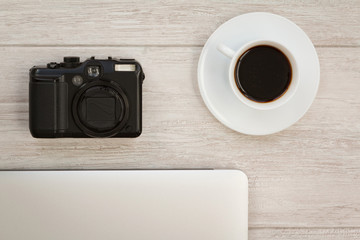 Camera next to a cup of coffee and a laptop